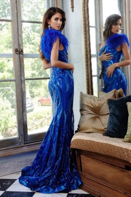 Model wearing Jovani 32596 royal blue gown with feather detail at shoulder, back view.